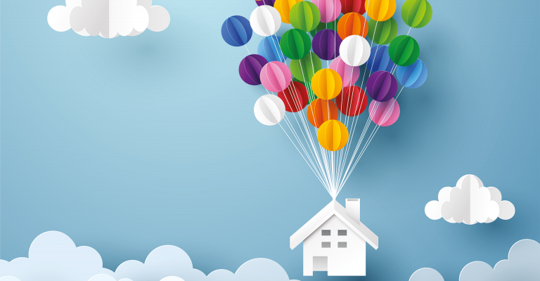 Papieren wit huis hangt aan kleurrijke ballonen met op de achtergrond een blauwe lucht en wolken